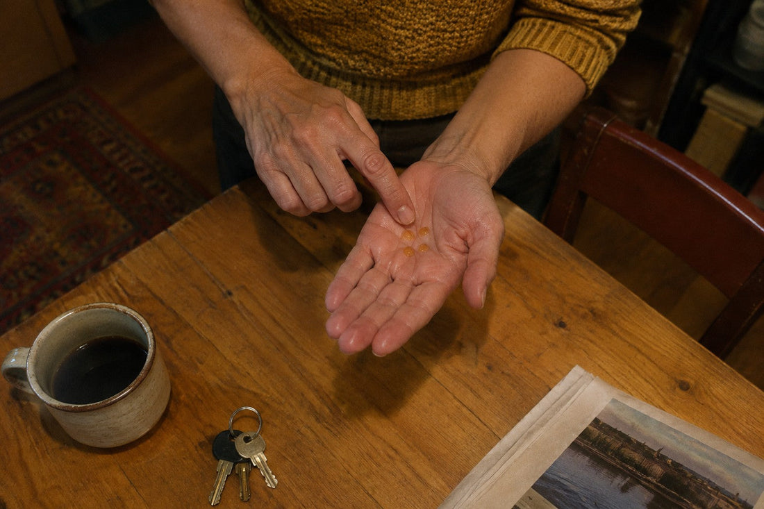 Three small drops of argan oil in an open palm at a kitchen table