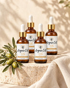 Four bottles of Argan Oil on travertine and cream linen with an argan sprig